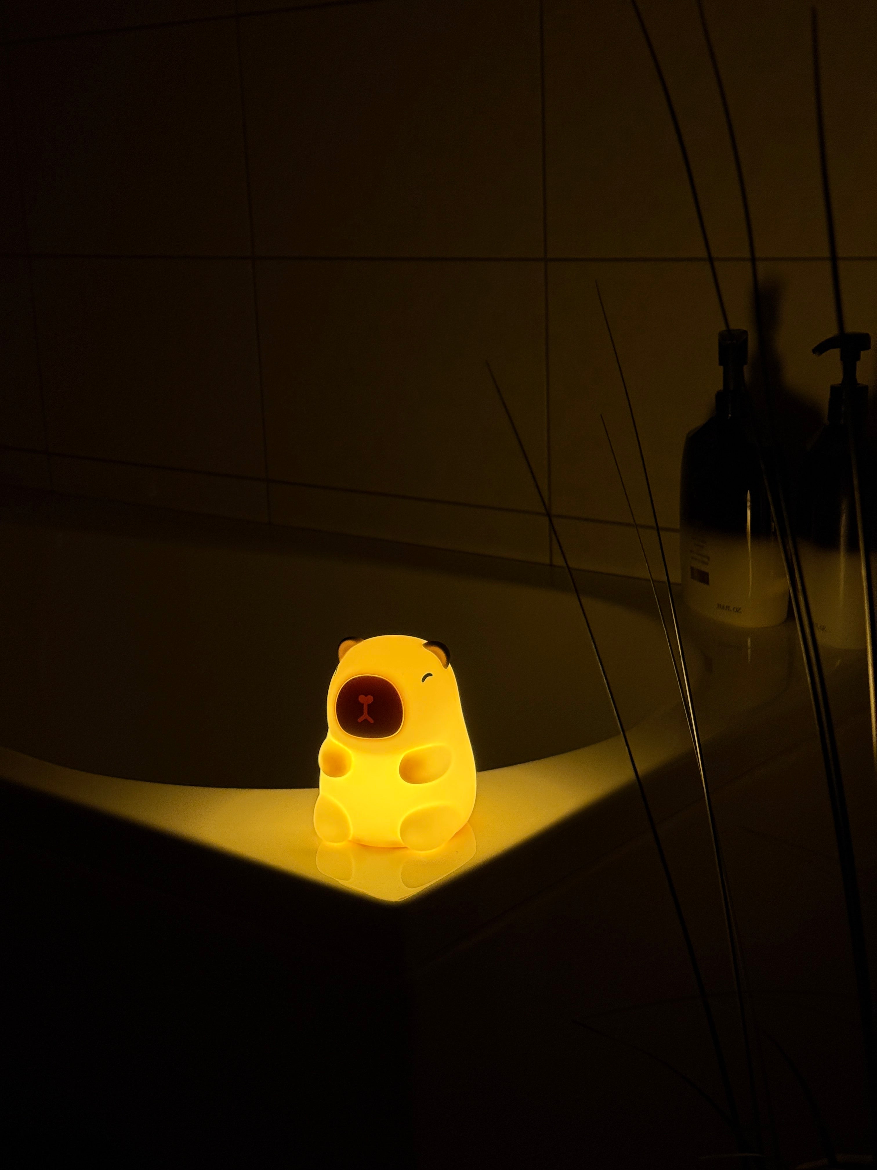 Yellow light bulb with a face design hanging from wires against a dark background