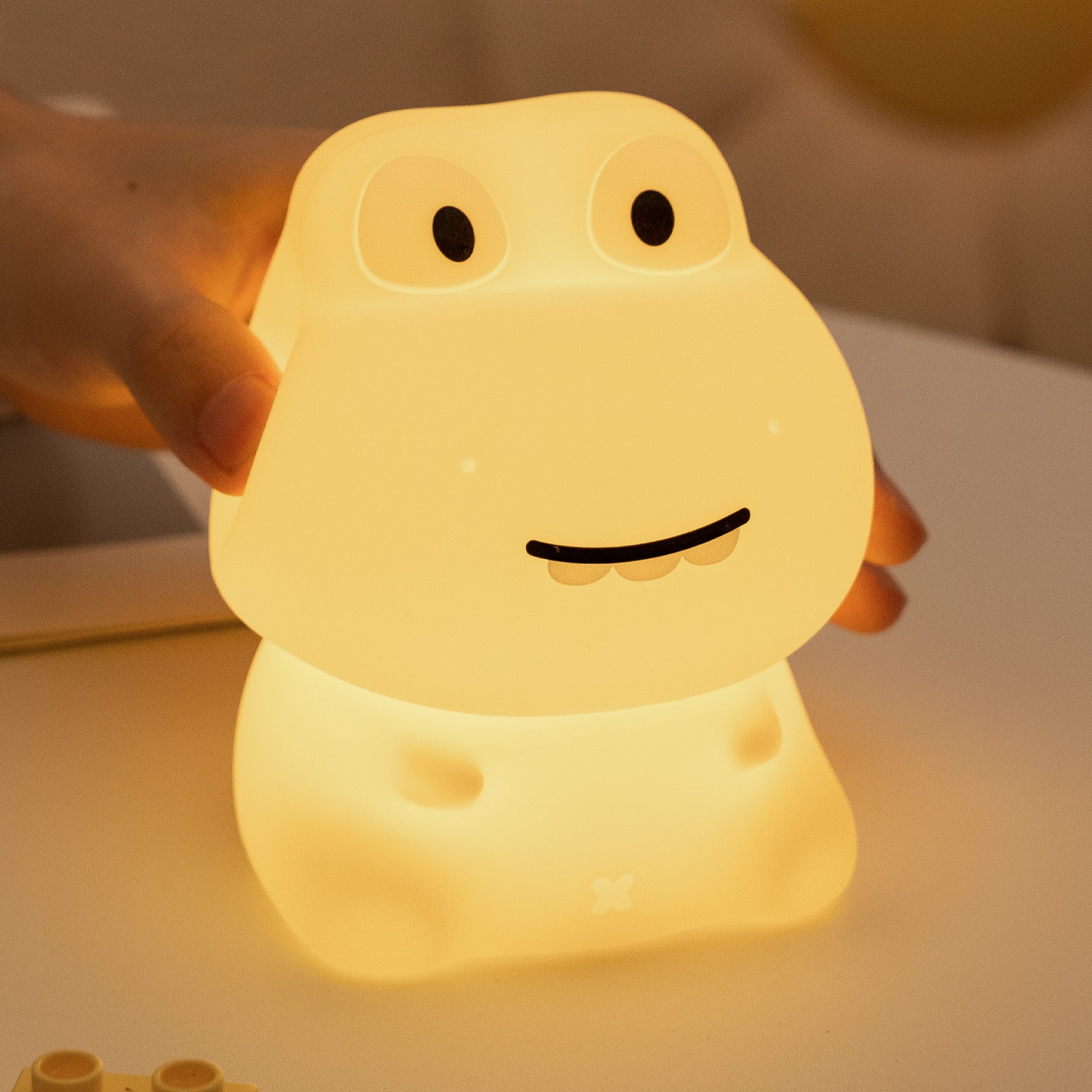 Cute dinosaur-shaped night light being held by a hand with a warm glow.