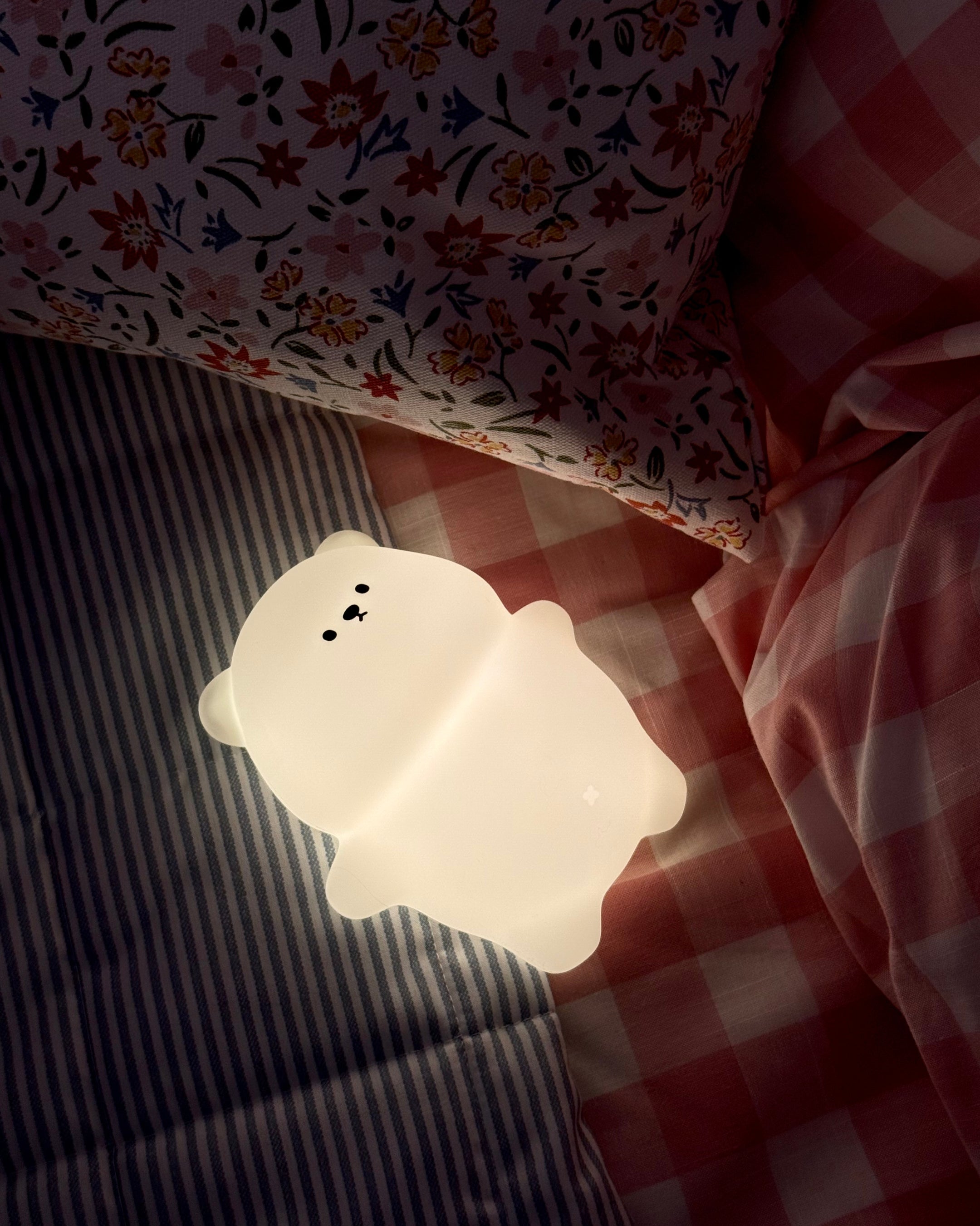 Cute white bear-shaped night light on a checkered fabric background