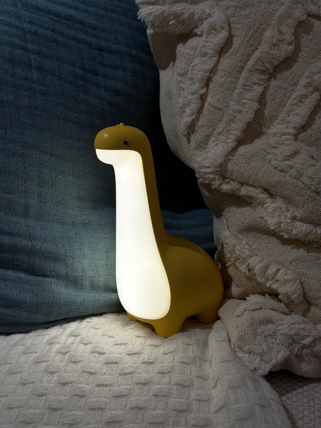 Yellow dinosaur night light on a textured surface