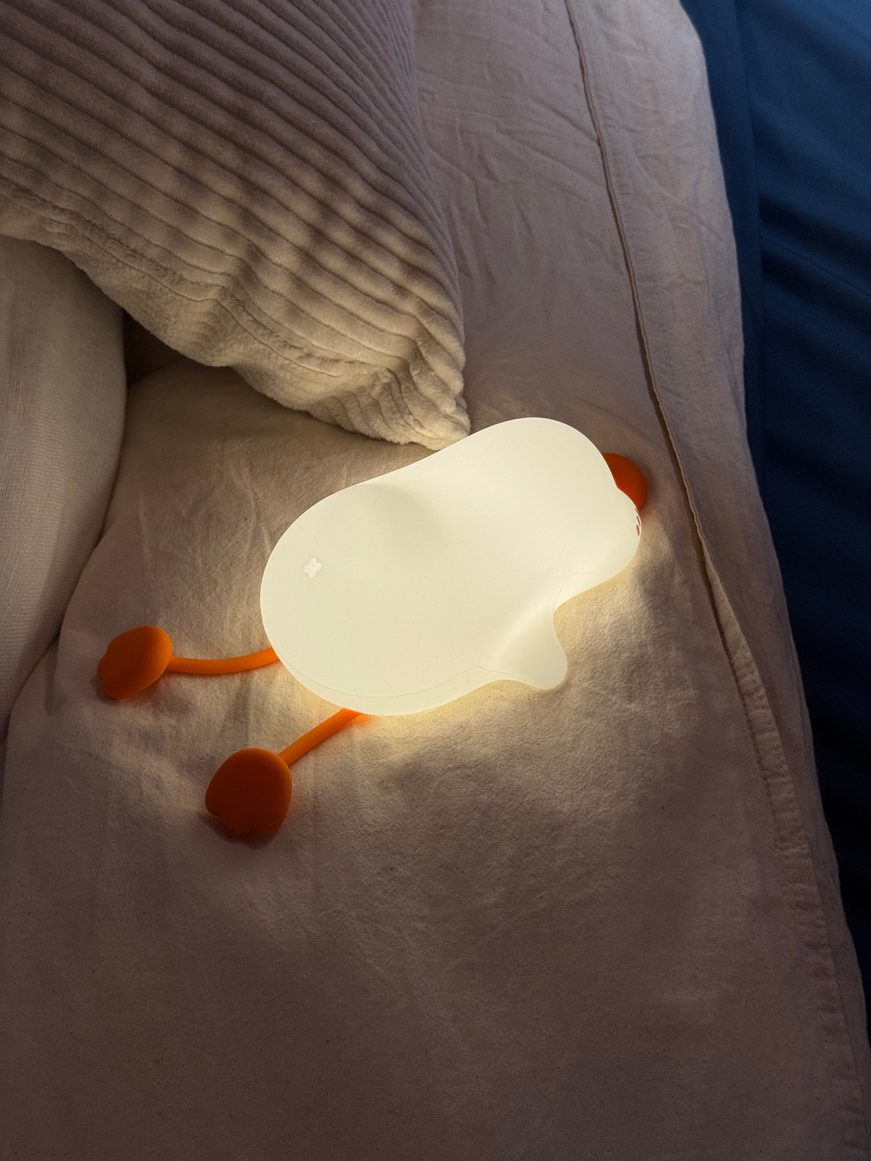 Light-up goose-shaped pillow on a bed