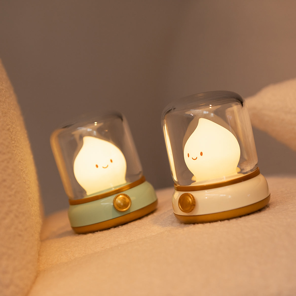 Two small night lights with smiling faces on a soft surface.