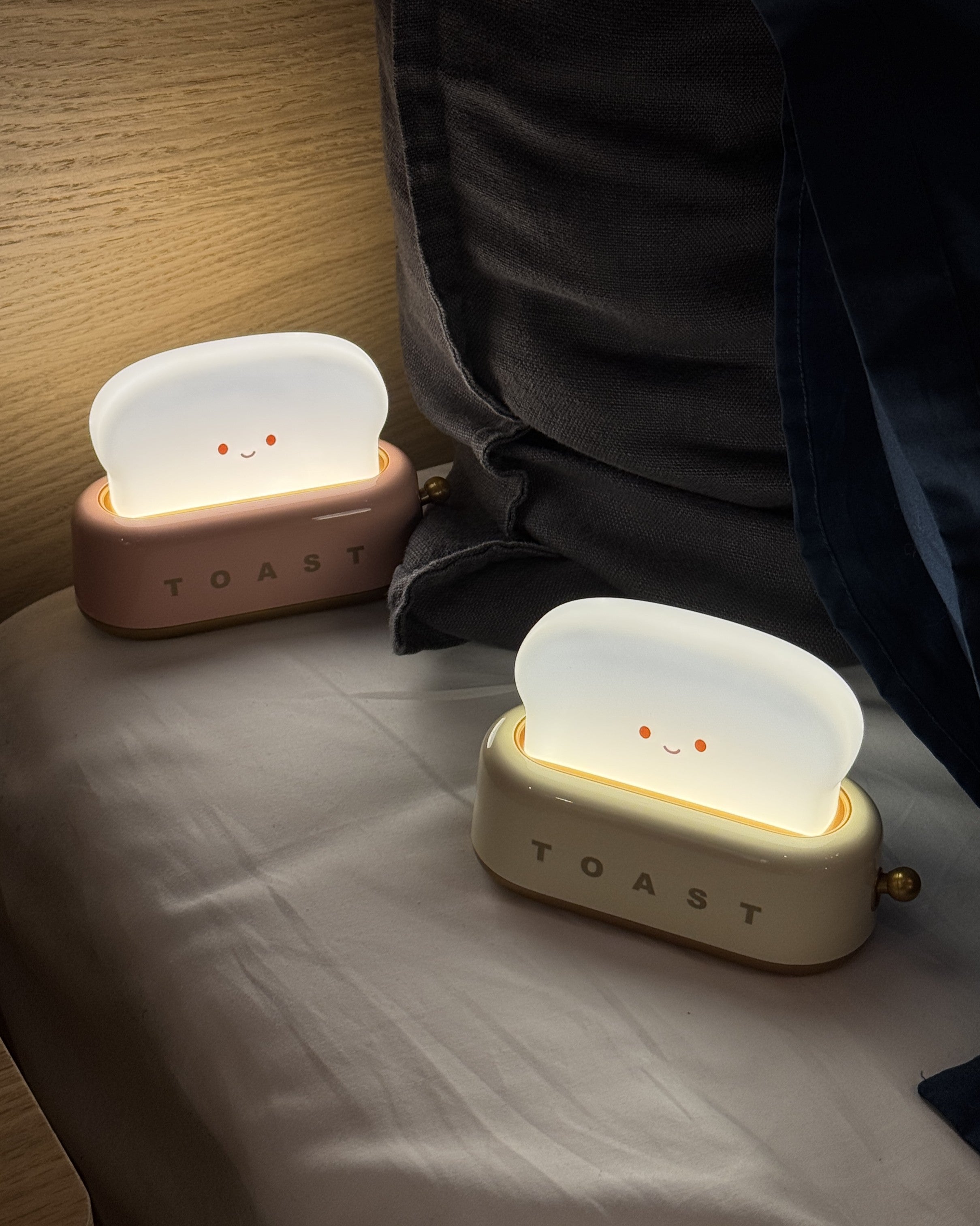 Two cute toaster night lights on a bed with a soft glow.