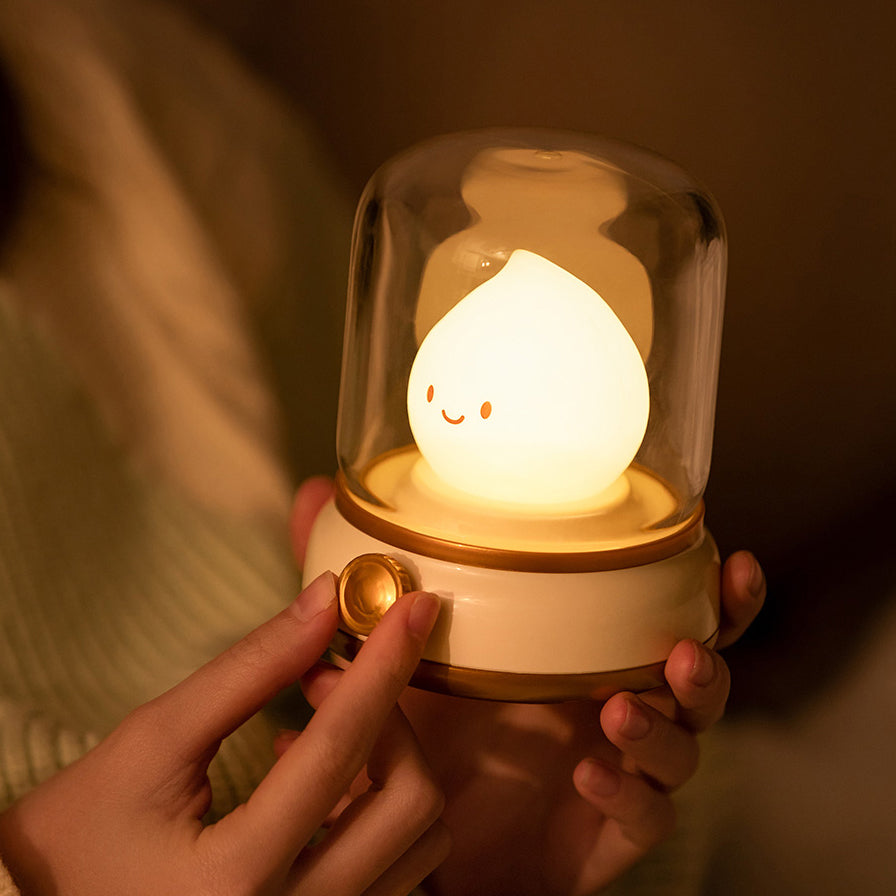 Cute lamp with a smiling face inside a glass dome held by a person.