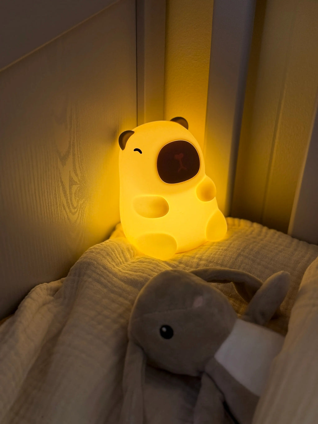 Cute night light shaped like a capybara on a bed with soft lighting