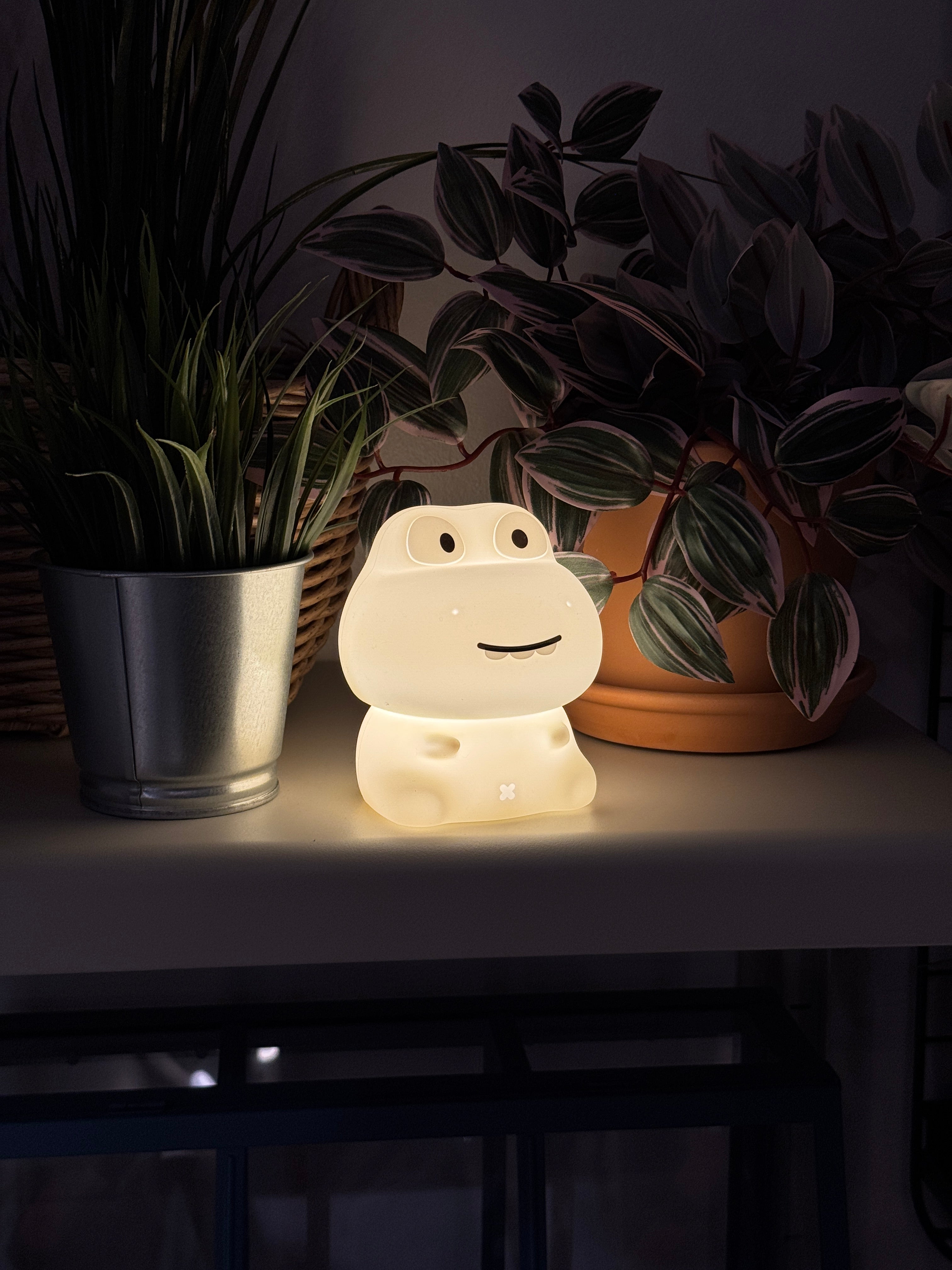 Decorative night light shaped like a dinosaur with plants in the background