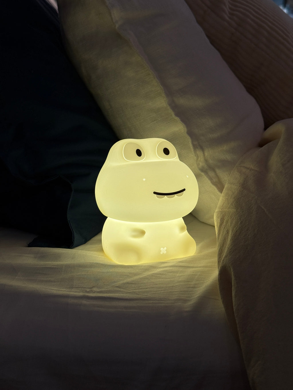 Glowing dinosaur-shaped night light on a bed